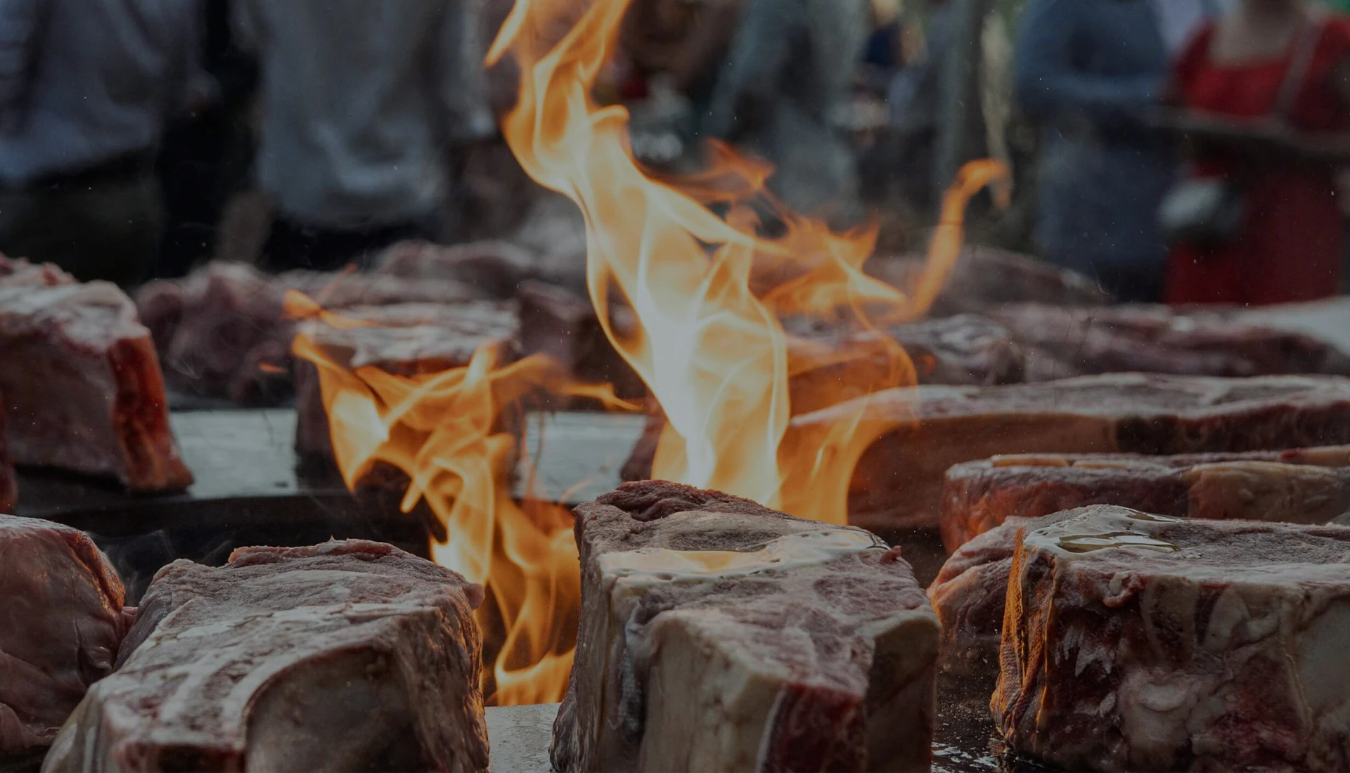 Côtes de bœuf grillant sur un brasero avec flammes vives en extérieur